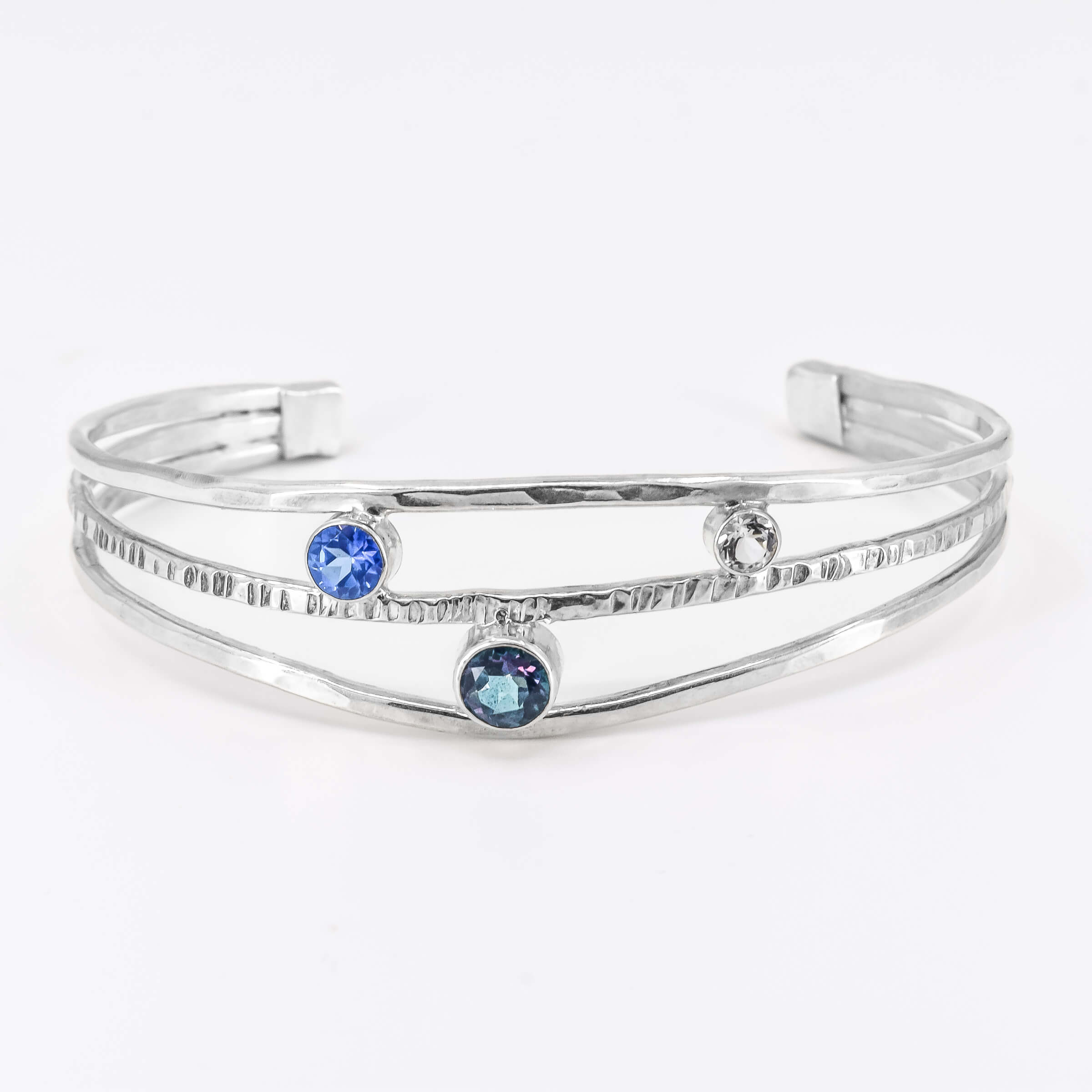 Faceted topaz gemstones in sterling silver cuff bracelet featuring a rainbow topaz, ice blue topaz and white topaz in various sizes.