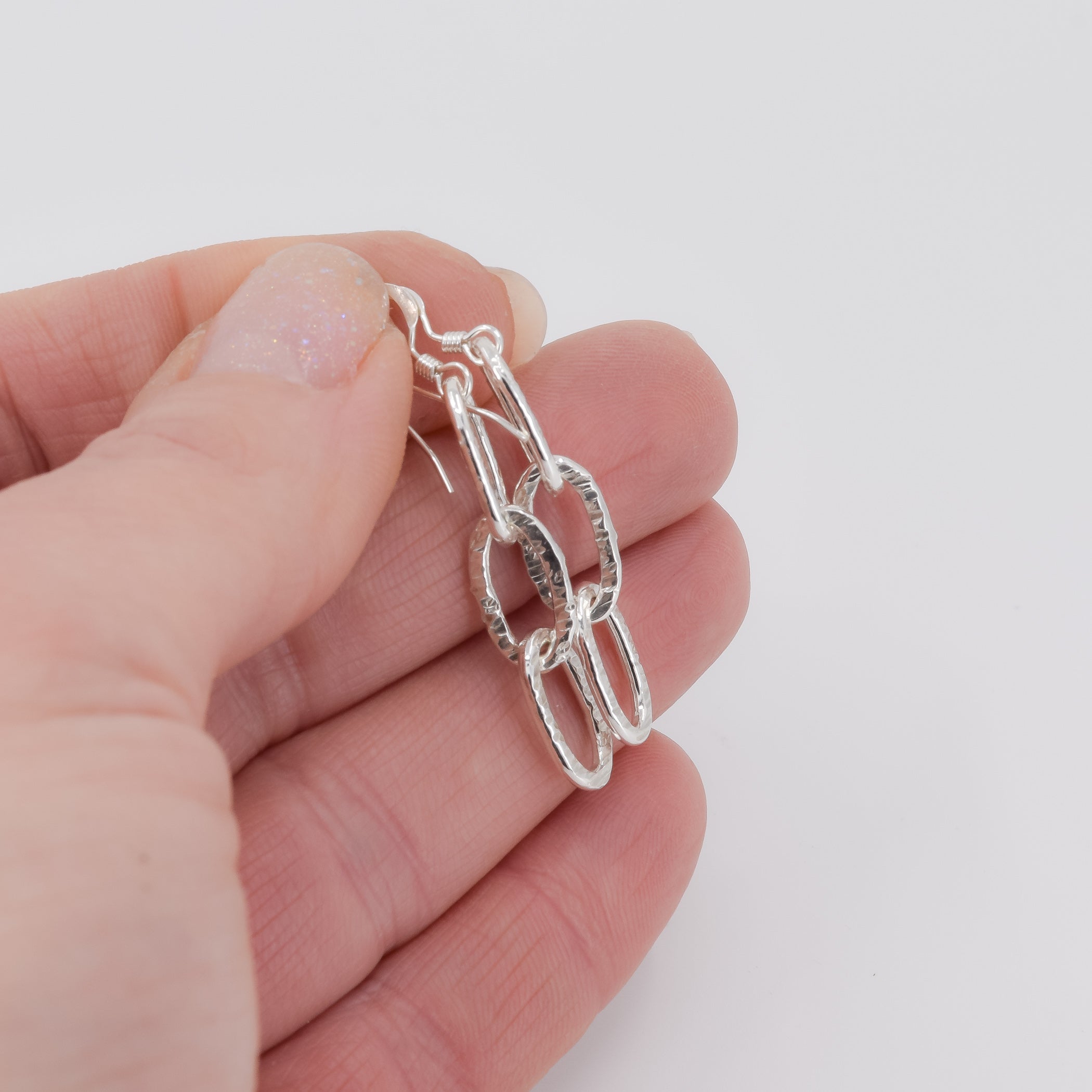 Birch tree bark textured sterling silver drop earrings shown in hand for size