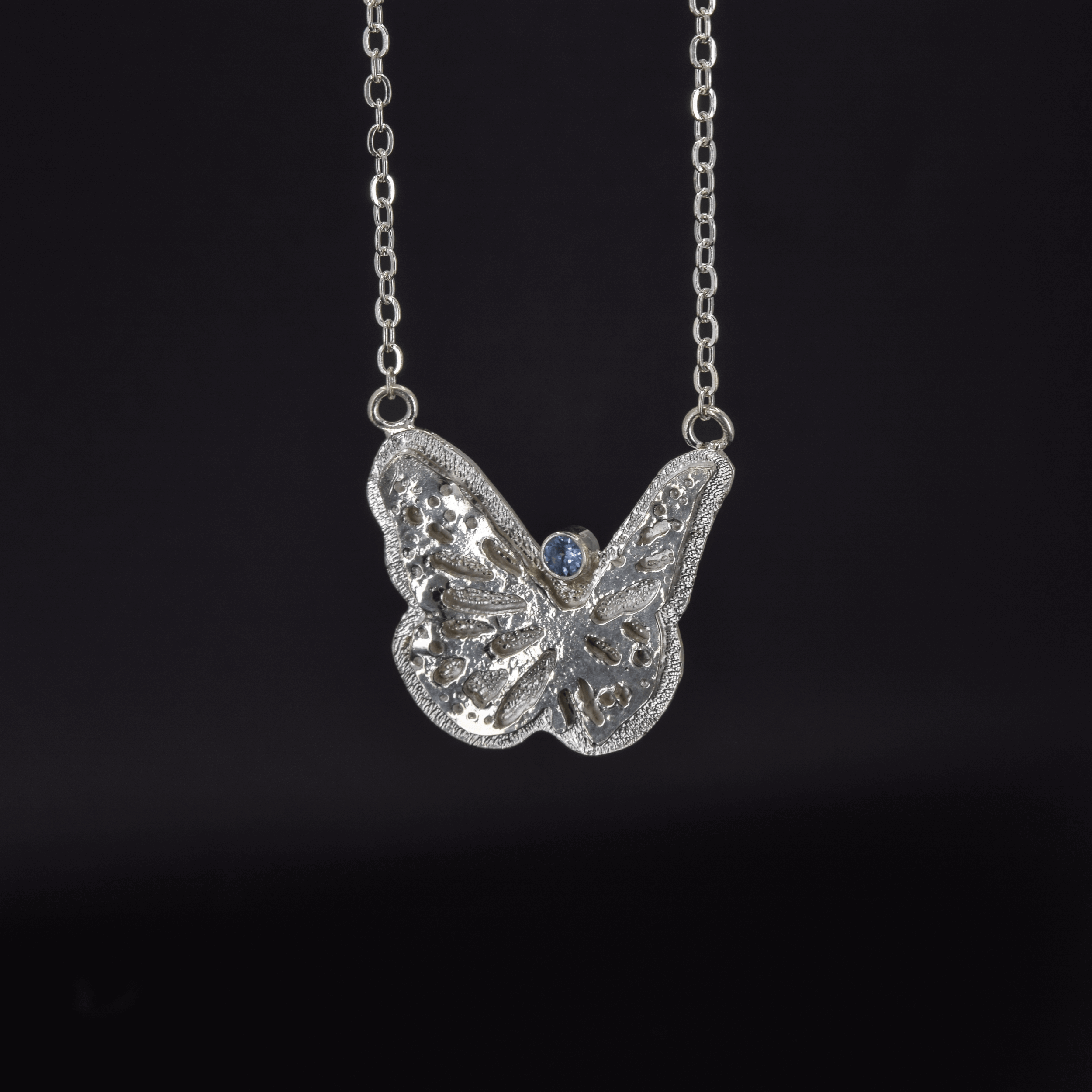 Large butterfly necklace in sterling silver with a faceted Teal Montana Sapphire round stone