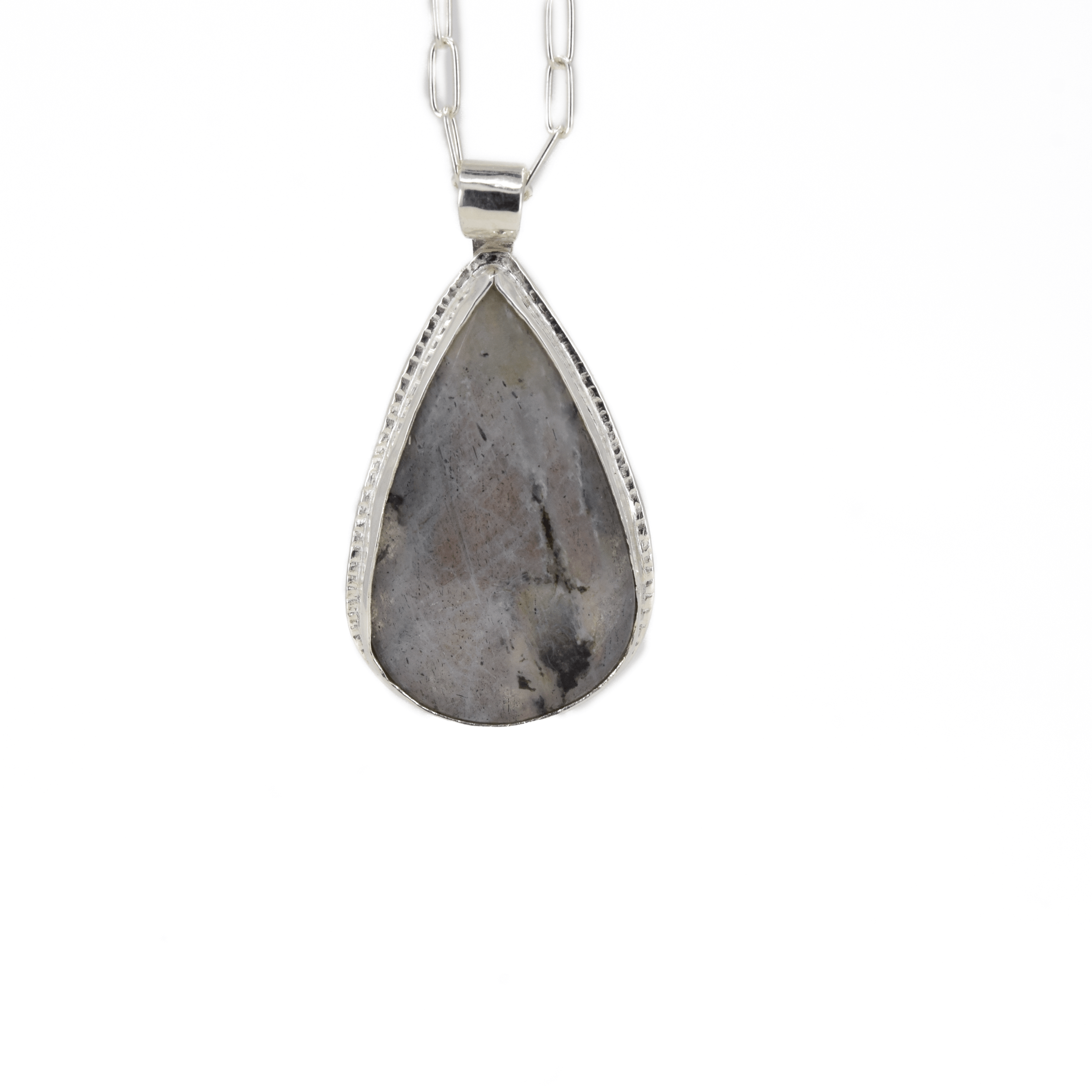 Teardrop shaped silver labradorite pendant with flashes of rainbow colors set in sterling silver, with a hand textured decorative border surrounding the stone and hanging from a paperclip style chain