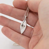 small hugged pendant necklace in sterling silver with a stardust texture and a 4mm Morganite faceted stone shown in hand for scale