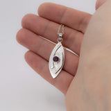 large hugged pendant necklace in sterling silver with a stardust texture and a 5mm Rhodolite garnet faceted stone shown in hand for scale
