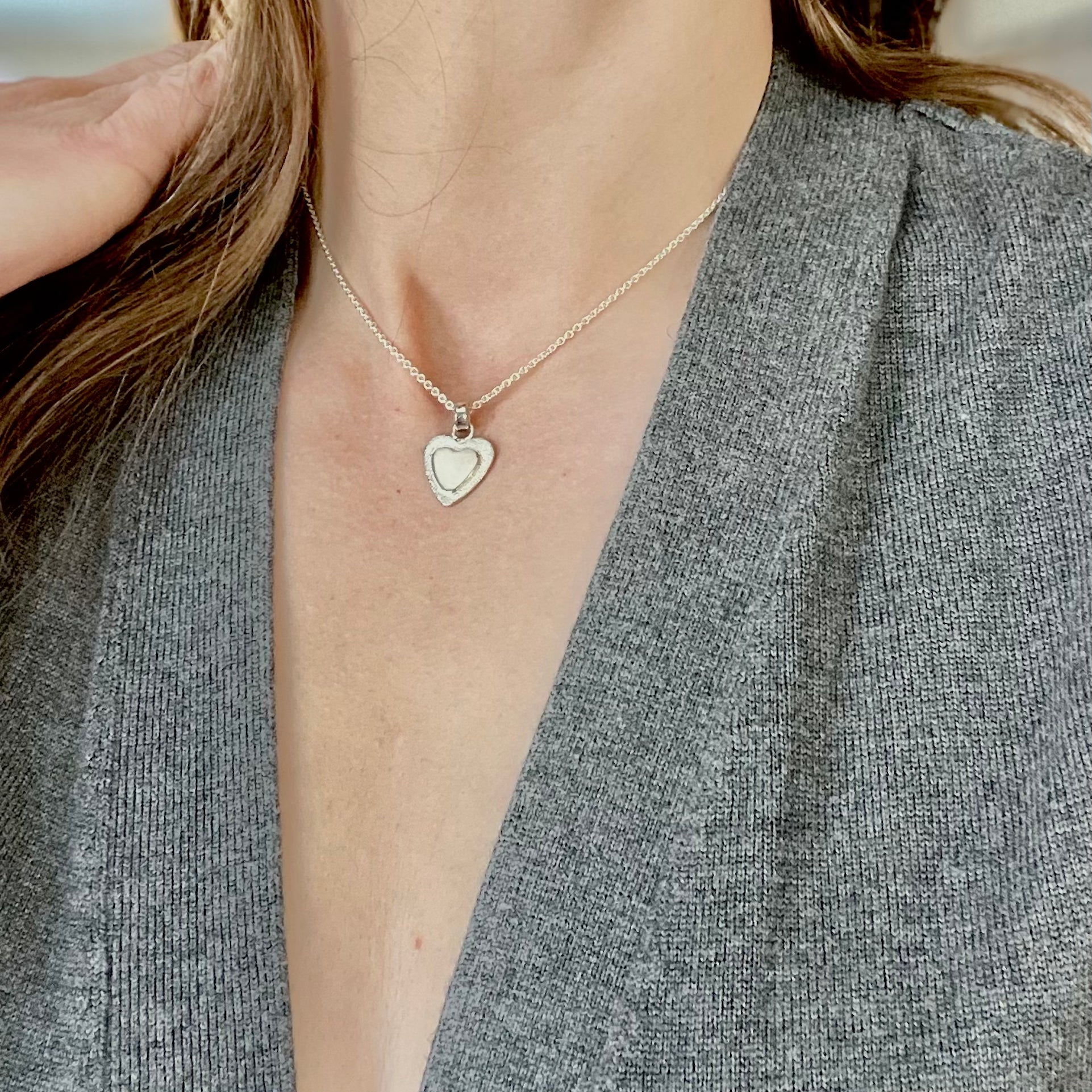 Sterling silver heart pendant with stardust texture shown on model