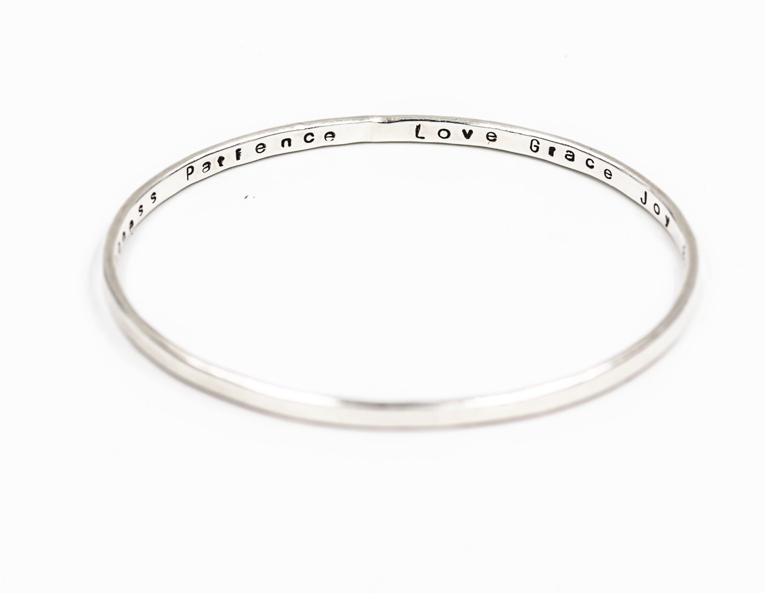 sterling silver bangle bracelet with the words "joy", "love", "patience", "grace", "joy", "faith" stamped on the inside. 